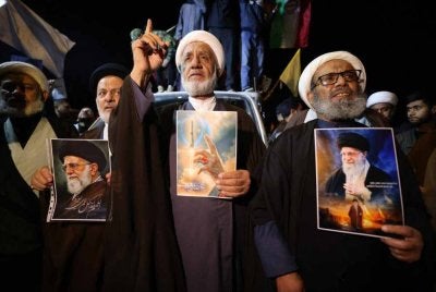 Ulama Syiah Iraq memegang potret Ayatollah Ali Khamenei ketika protes membantah serangan AS-Israel ke atas Iran berhampiran Zon Hijau yang menempatkan Kedutaan AS di Baghdad. - AFP