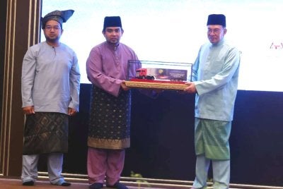 Anwar (kanan) menerima replika lori kontena selepas melancarkan Misi Bantuan Kemanusiaan 30 Kontena Malaysia ke Gaza pada Majlis Berbuka Puasa bersama Pemimpin Masyarakat Tempatan di Kompleks Seri Perdana pada Ahad. Foto Bernama