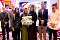 Norfadzliana (tiga dari kiri) dan ibunya, Asiah menerima sumbangan khairat kematian yang disampaikan oleh Siti Norina (tiga dari kanan) pada Pelancaran Skim Sejahtera dan Skim Kasih Warga Pendidik YGMB di Kota Bharu pada Isnin.