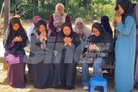 Siti Asiah (tengah) menyaksikan pengebumian jenazah dua anaknya di Tanah Perkuburan Islam Batas Ubi, Yan, Kedah.
