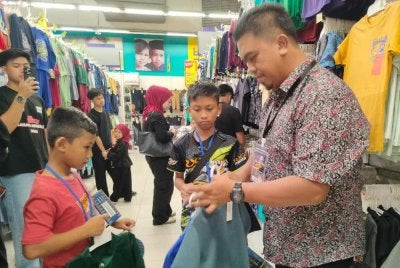 Mohd Nazari (kanan) membantu memilih pakaian dan kelengkapan Aidilfitri buat anak-anak yatim yang dibawa dari kawasan Parlimen Pasir Salai di Pasar raya Besar Mydin Meru Raya di sini pada Ahad.