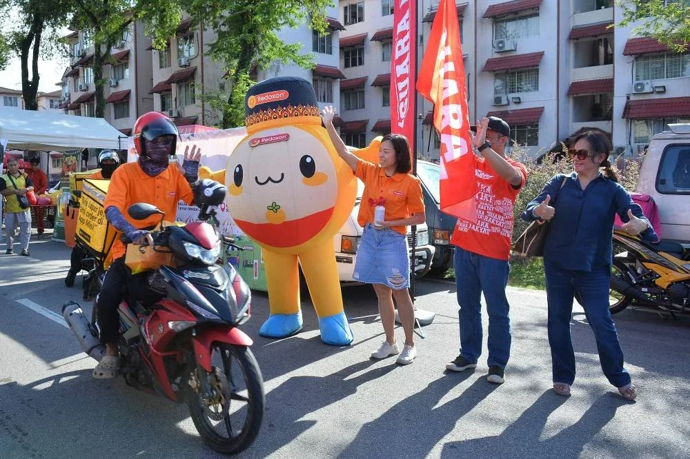 Wakil Redoxon membunyikan hon sebagai gimik isyarat untuk penunggang e-hailing memulakan perjalanan mereka menyampaikan bantuan pek iftar kepada rumah kebajikan.