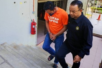 Suspek diiringi pegawai SPRM ketika dibawa ke Mahkamah Majistret Temerloh pada Selasa untuk permohonan perintah reman. - Foto: SPRM Pahang