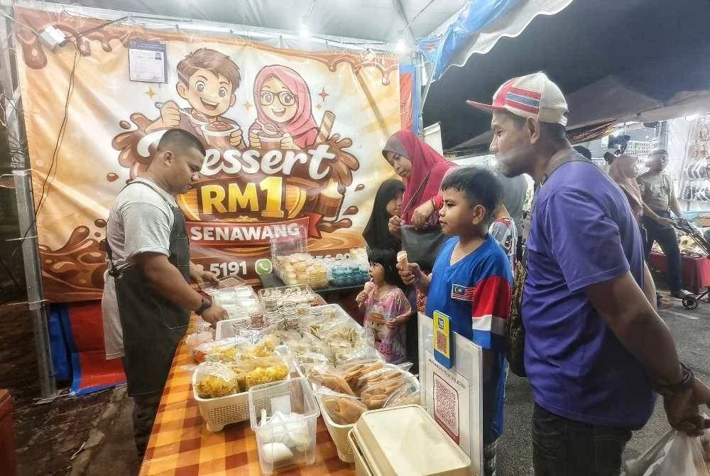 Muhammad Adha melayan pelanggan di gerainya di Dataran Senawang