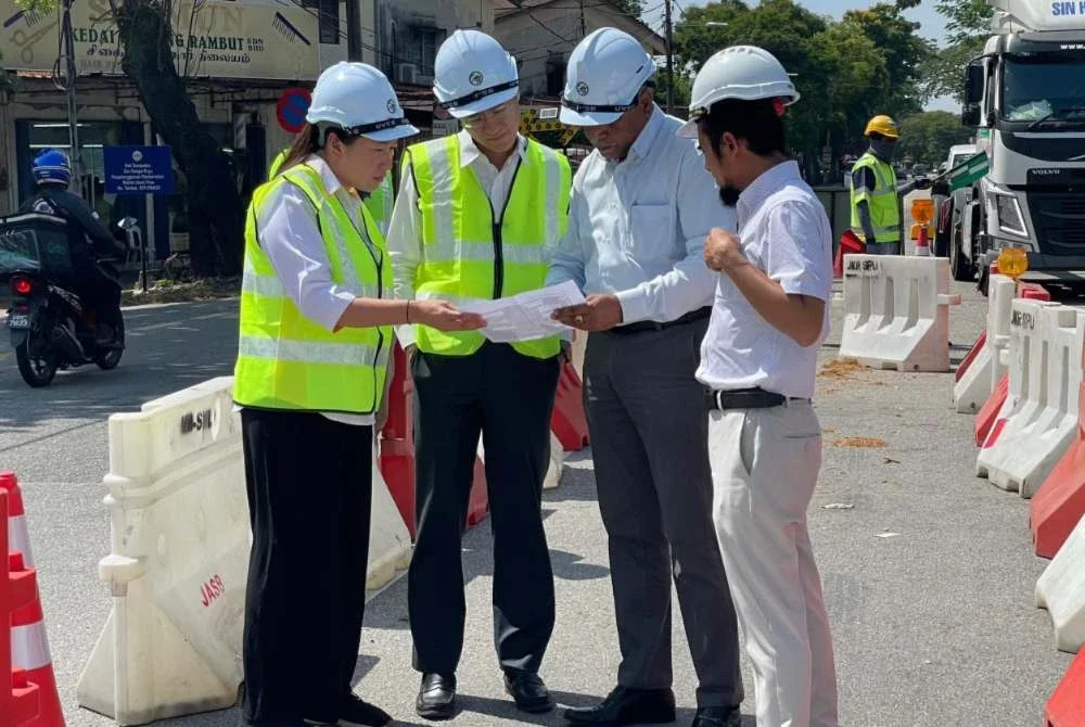Zairil (dua dari kiri) mendengar penerangan daripada pegawai bertugas mengenai perkembangan terkini lubang benam di Jalan Bagan Lalang.
