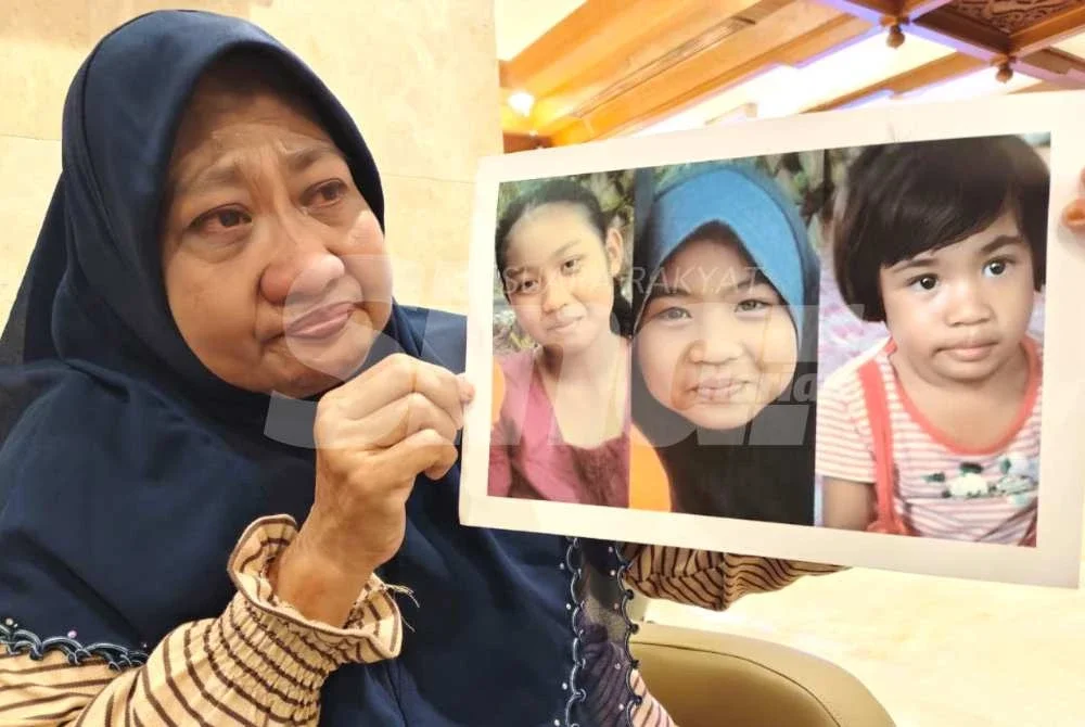 Siti Aishah tidak mampu menahan sebak ketika memegang gambar tiga anaknya yang meninggal dunia akibat dibunuh, 13 tahun lalu.Foto Sinar Harian