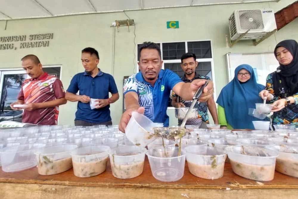 Kakitangan MARDI tekun mencedok bubur lambuk ke dalam bekas plastik untuk diagihkan.