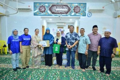 Raja Nurmaria Murni (tiga dari kiri) bersama Firdaus (tengah) diiringi Nik Justin (empat dari kanan) dan Ahmad Faudzi (tiga dari kanan) menyampaikan sumbangan kotak makanan dan al-Quran kepada keluarga miskin bandar di Pangsapuri Melati.