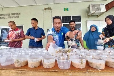 Kakitangan MARDI tekun mencedok bubur lambuk ke dalam bekas plastik untuk diagihkan.