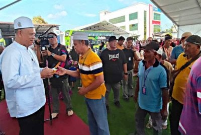 Che Ibrahim (kiri) menyampaikan sumbangan zakat kepada penerima pada Majlis Penyampaian Zakat E-Mutiara di Kota Bharu pada Khamis.