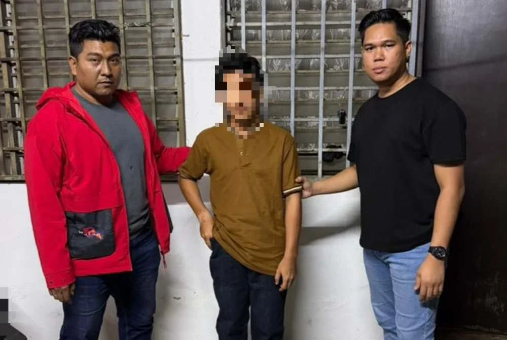 Suspek (tengah) ditahan polis di Pasir Gudang. Foto: PDRM