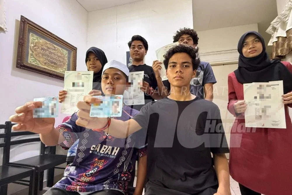 Khalid (duduk, kanan) menunjukkan MyKad dan sijil kelahiran bersama adik-beradiknya. 