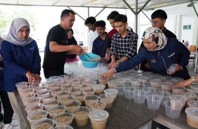 Staf MyDigital ID bersama pelajar menyediakan bubur lambuk.