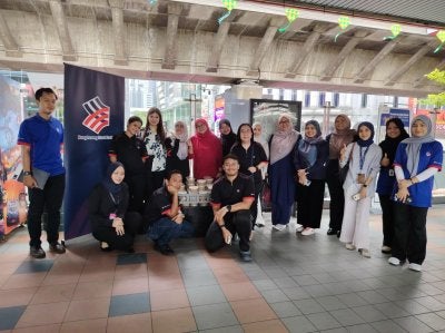 Kakitangan Hong Leong Islamic Bank bergambar ketika mengagihkan bubur lambuk kepada orang ramai di sekitar Masjid Jamek Kuala Lumpur.