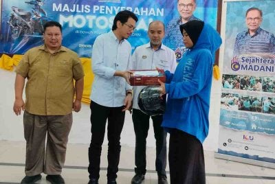 Muhammad Kamil (dua dari kiri) menyampai sumbangan kepada penerima sempena Majlis Penyerahan Motosikal di bawah Inisiatif Sejahtera Madani di Dewan Komuniti Sungai Tapah, pada Jumaat.