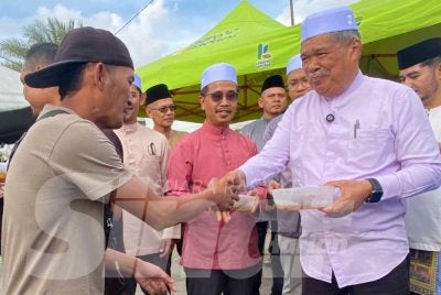 Mohamad (kanan) menyampaikan sumbangan juadah berbuka kepada orang ramai pada Program Sentuhan Agro Madani: Karnival Cahaya Aidilfitri KPKM 2026 di RTC Tunjong di Kota Bharu pada Jumaat. 
