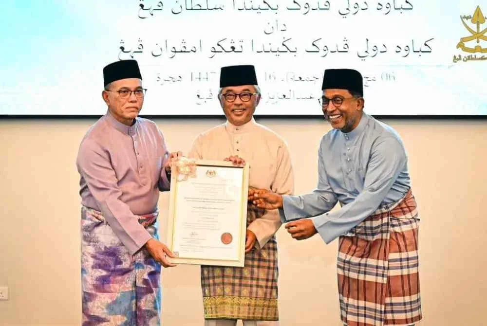 Al-Sultan Abdullah berkenan menerima warkah perisytiharan nama UNIQSAAS daripada Zambry (kanan) sebelum berkenan menyerahkan warkah berkenaan kepada Wan Rosdy (kiri) sebagai simbolik pengisytiharan rasmi universiti tersebut. Foto FB Kesultanan Pahang