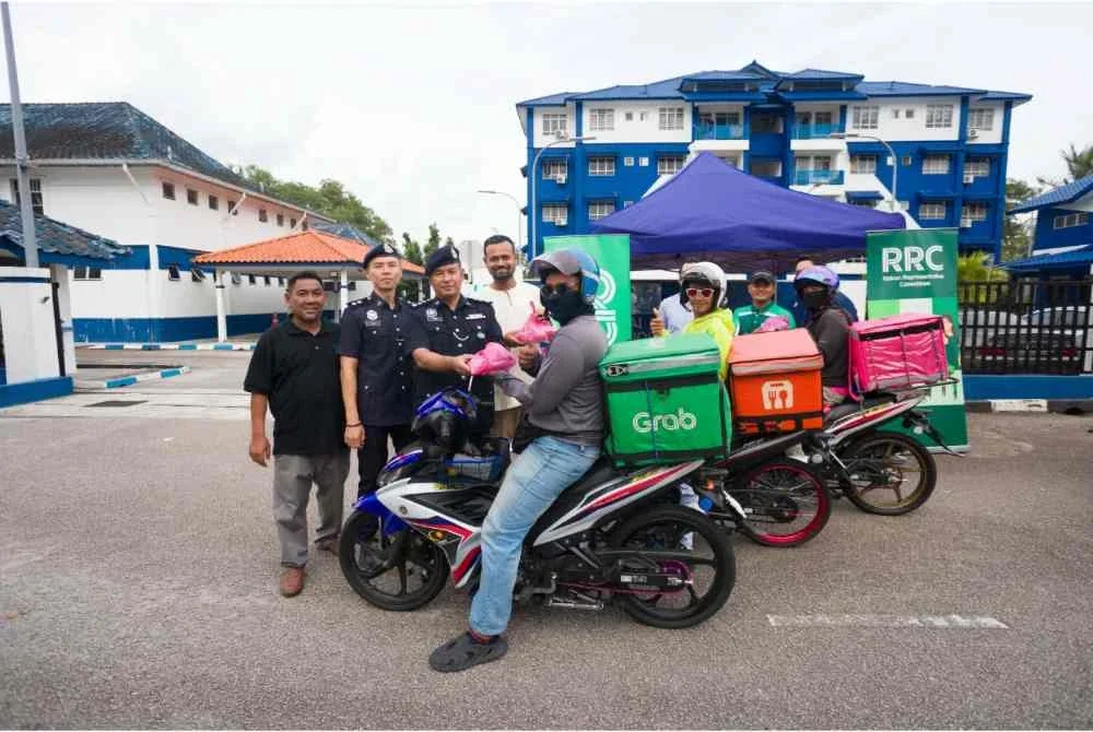 Ketua Bahagian Jabatan Pencegahan Jenayah dan Keselamatan Komuniti (JPJKK) IPD Seri Alam, Asisten Superintenden Mat Nawi Ab Rahman (tiga dari kiri) bersama Abdul Hakim mengagihkan pek berbuka puasa kepada penghantar p-hailing di Balai Polis Johor Jaya petang Jumaat.