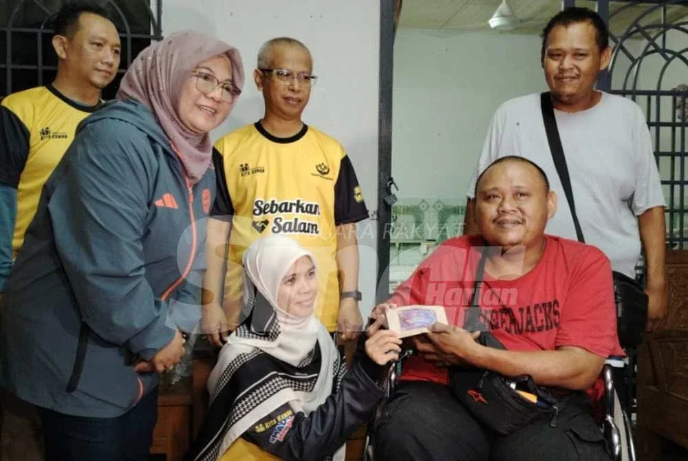 Marhamah (tengah) menyampaikan sumbangan kepada penerima pada program Singgah Sahur pada Sabtu.