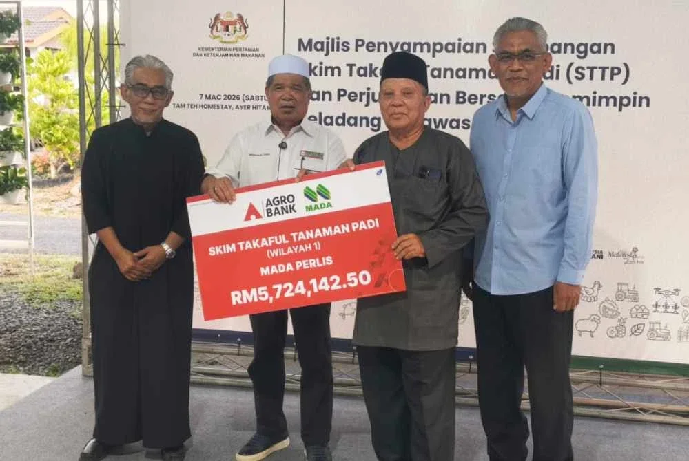 Tengku Ahmad Badli Shah (kiri) mengiringi Mohamad (dua dari kiri) menyampaikan sumbangan STTP kepada pesawah di Ayer Hitam, Jerlun pada Sabtu.