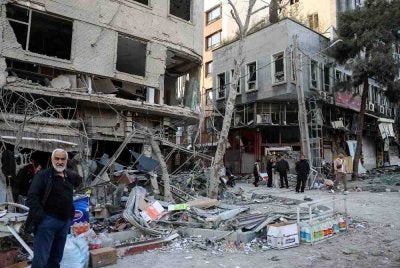 Seorang penduduk berdiri di tepi jalan berhampiran bangunan kediaman yang rosak berhampiran Dataran Niloufar di Teheran, selepas kempen ketenteraan Amerika Syarikat-Israel terhadap Iran pada 2 Mac lalu. Foto: AFP