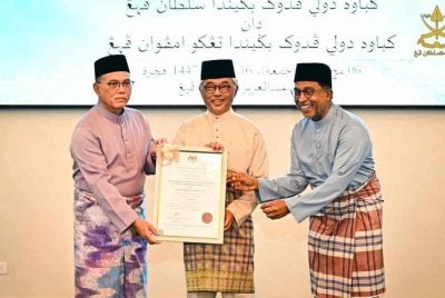 Al-Sultan Abdullah berkenan menerima warkah perisytiharan nama UNIQSAAS daripada Zambry (kanan) sebelum berkenan menyerahkan warkah berkenaan kepada Wan Rosdy (kiri) sebagai simbolik pengisytiharan rasmi universiti tersebut. Foto FB Kesultanan Pahang 