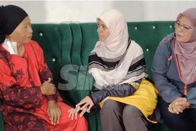 Marhamah (tengah) diiringi Tuminah (kanan) menyampaikan sumbangan kepada penerima pada program Singgah Sahur pada Sabtu.