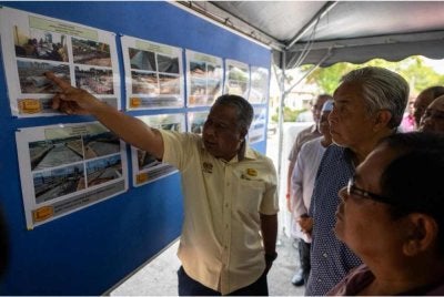 Ahmad Zahid (kanan) mendengar taklimat disampaikan Pengarah JKR Perak, Zamri Mat Kassim mengenai laluan baharu berkenaan.