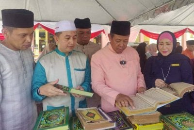 Mohd Razlan (dua dari kanan) dan Norlaili (kanan) melihat naskhah al-Quran lama semasa Program Sinar Ramadan di Masjid Ma’Muniah Simpang Lima, Sungai Besar pada Sabtu.
