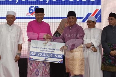 Ahmad Zahid (dua dari kiri) menyampaikan cek cura kepada wakil peserta Felcra Berhad Negeri Sarawak pada Majlis Santunan Kasih Ramadan KKDW di Masjid Tuminah Hamidi pada Sabtu.