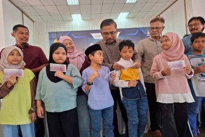 Mohamad Yusri (tengah) menyantuni sebahagian penerima Program Meriah Beraya Sejahtera Bersama 2026 DUN Ayer Kuning di Dewan Serbaguna Kampung Tersusun Haji Tahir pada Ahad.