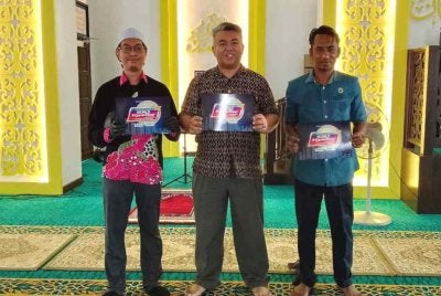 Kakitangan Masjid Bandar Al-Wathiqubillah di Kuala Nerus memegang plakad World #QuranHour yang akan berlangsung di masjid berkenaan pada 11 Mac ini.