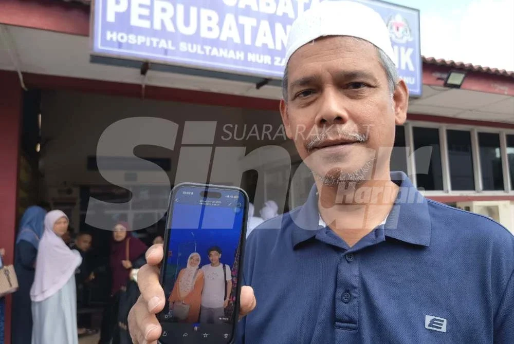 Ahmad Azhar menunjukkan gambar arwah anak sulungnya bersama isterinya ketika ditemui di Jabatan Perubatan Forensik HSNZ di Kuala Terengganu pada Isnin.