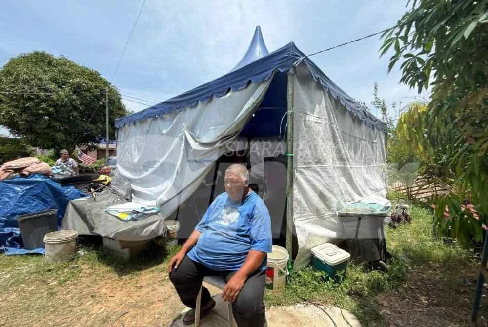 Mohd Khairi duduk di khemah yang menjadi tempat tinggal sementara menunggu rumah mereka siap.