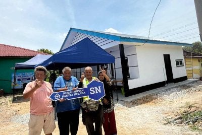 Empat daripada enam beradik OKU lembam bergambar di depan rumah baharu yang bakal mereka duduki dalam masa terdekat.
