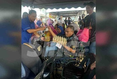 Mohd Yusoff (kiri) menyampaikan sumbangan kepada penerima berkerusi roda. 