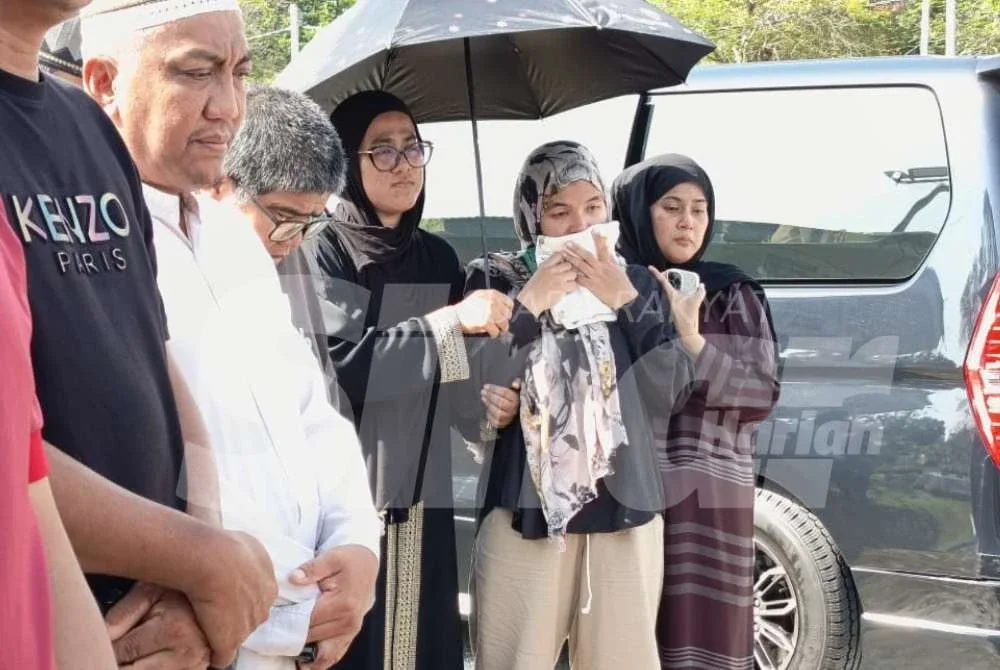 Ummu Habibah (dua dari kanan) tidak dapat menahan sebak ketika menyaksikan pengebumian anak sulungnya.