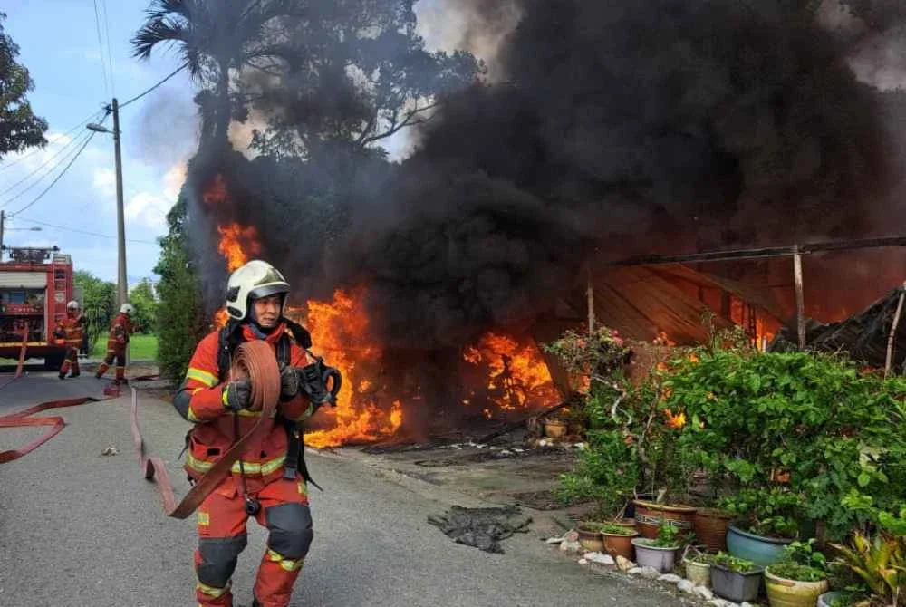 Anggota bomba dan penyelamat bertungkus-lumus memadamkan kebakaran dua rumah di Kampung Kepayang, Fair Park pada Selasa. Foto JBPM Perak