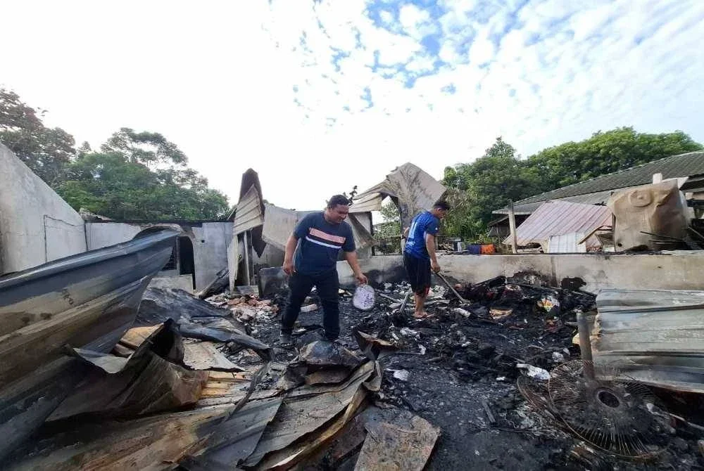 Muhamad Azrizal (kiri) bersama abangnya, Muhamad Asyraf Abas, 29, meninjau keadaan kediaman mereka yang musnah dalam kebakaran ketika tinjauan Sinar Harian pada Rabu.