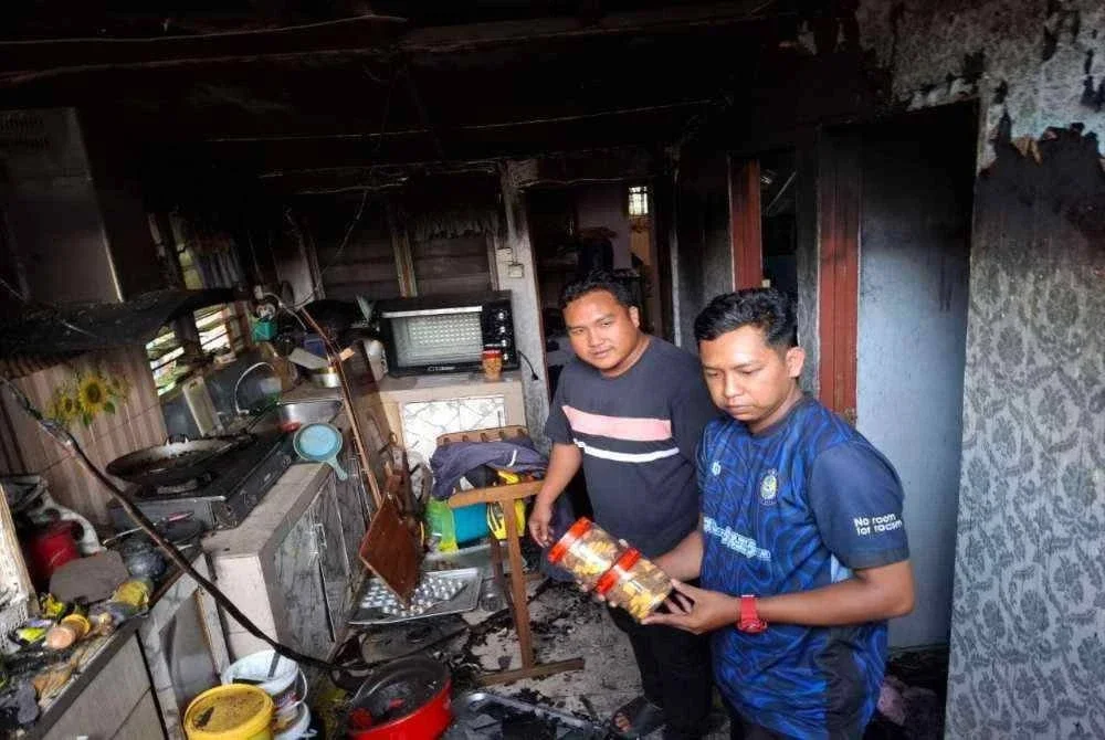 Muhamad Azrizal (kiri) bersama abangnya, Muhamad Asyraf Abas, 29, menunjukkan kuih dan keadaan ruang dapur yang musnah dalam kebakaran ketika tinjauan Sinar Harian pada Rabu.