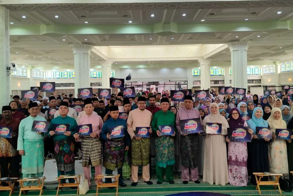 Mohd Zahidi (tengah) bersama tetamu dan peserta yang hadir menunjukkan plakad World #QuranHour selepas selesai program berkenaan di Masjid Negeri Perak di sini pada Rabu.