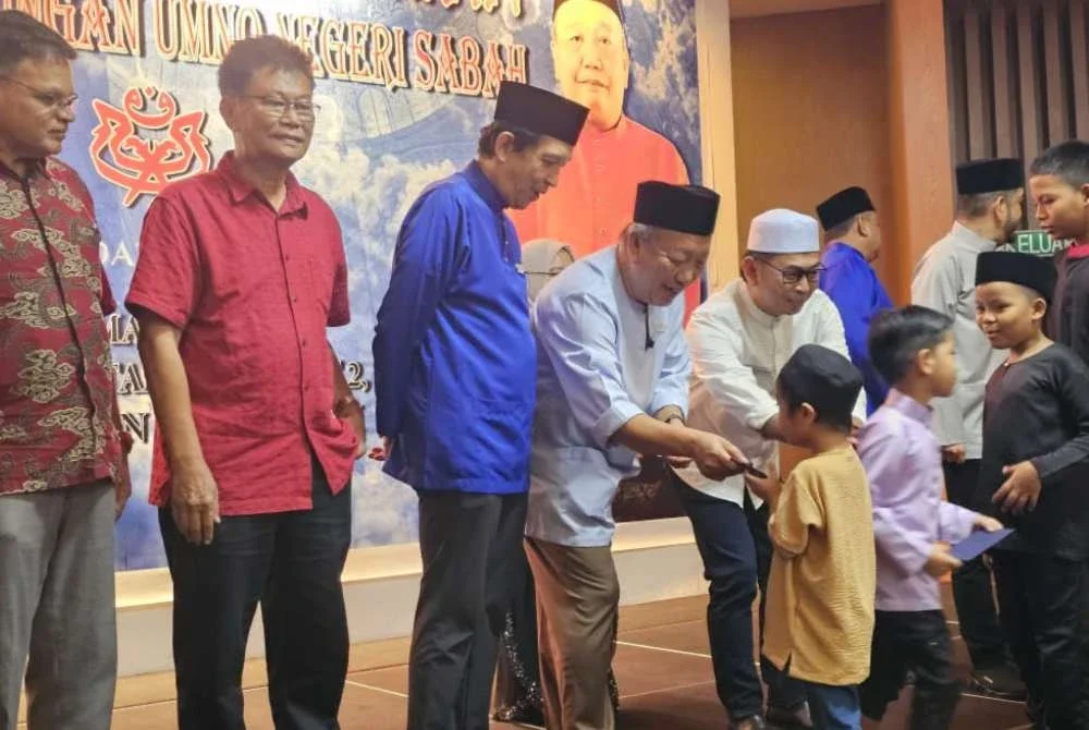 Jafry (empat dari kiri) menyampaikan sumbangan kepada kanak-kanak pada majlis berbuka puasa di bangunan UMNO, Kota Kinabalu.