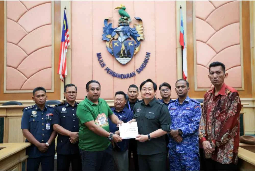 Walter (tiga dari kanan) yang mewakili kerajaan negeri menyampaikan bantuan wang ihsan kepada Lionel, anak kepada mangsa tanah runtuh, mendiang Agustine Frederick J. Lingam pada Majlis Penyerahan Bantuan Wang Ihsan kepada waris mangsa tanah runtuh di pejabat MPS pada Khamis. Foto Bernama
