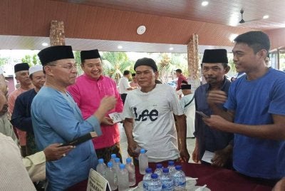 Hasni (kiri) menyerahkan bantuan Kasih Johor di Benut.