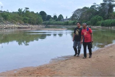 Fadli (kanan) bersama Amran (kiri) meninjau keadaan air Sungai Golok yang surut berikutan cuaca panas berdekatan Pos Ibrahim Pencen. Foto Bernama