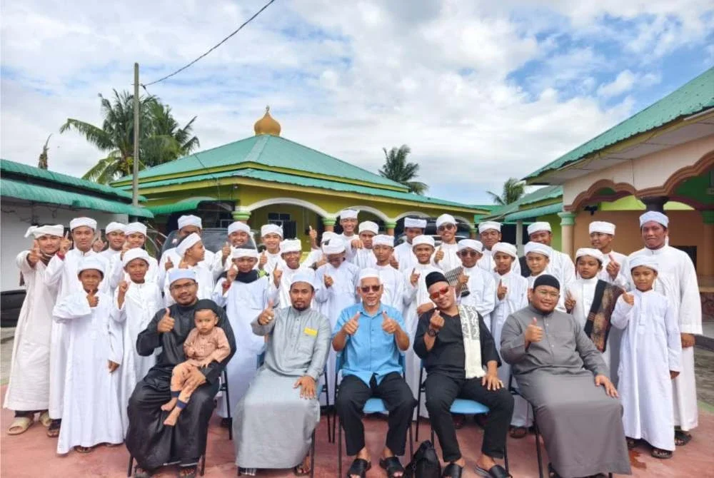 Pelajar Madrasah Tahfiz Asy-Syakirin yang menuntut al-Quran bergambar bersama guru mereka.
