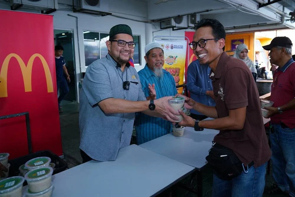 Kakitangan McDonald’s Malaysia memberikan bubur lambuk kepada salah seorang penduduk.