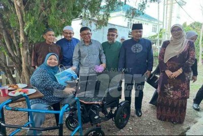 Sumbangan kerusi roda disampaikan Roslan (tiga dari kiri) kepada penerima. 