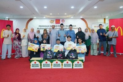 Ahmad Fauwaz (belakang, tujuh dari kiri) dan Azhar (belakang, lapan dari kiri) bergambar bersama penerima sumbangan dalam Program Kongsi Rezeki Ramadan McDonald’s Malaysia dan JAWI Food Bank di Masjid Al-Imam, Ash- Shafie, Taman Maluri pada Sabtu.