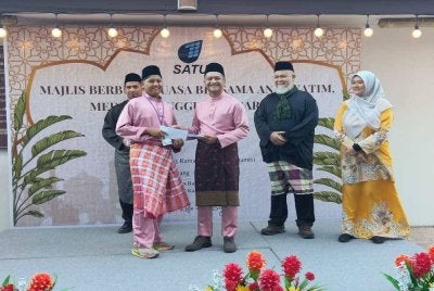 Abdul Karim (tiga dari kanan) menyampaikan sumbangan kepada tetamu yang hadir sempena Majlis Iftar Bersama Anak-Anak Yatim dan Media di Hotel Permai, Kuala Terengganu pada Khamis.